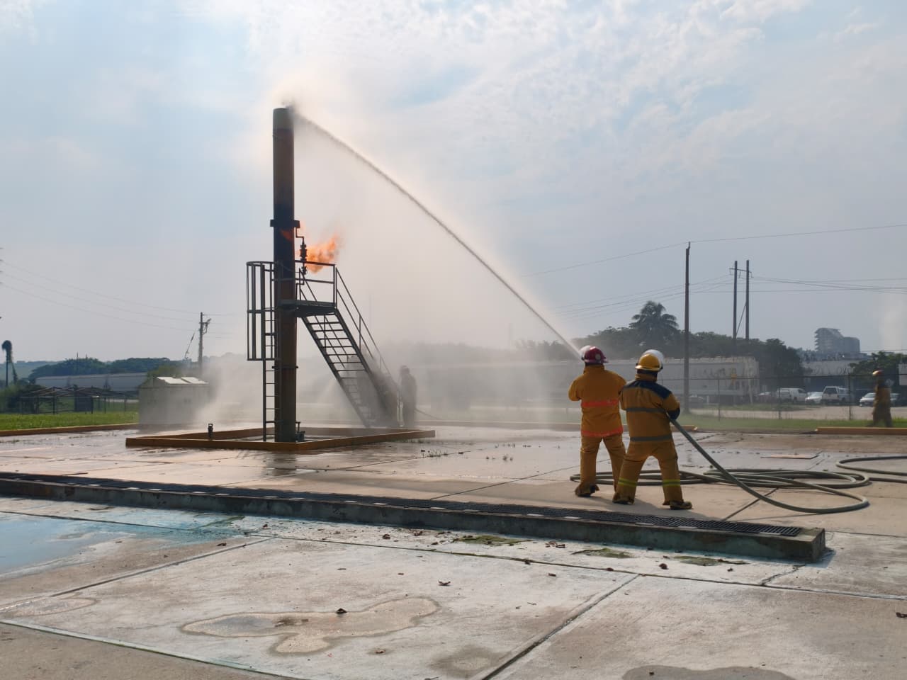 Dos brigadistas operan una manguera durante un ejercicio de control de incendios